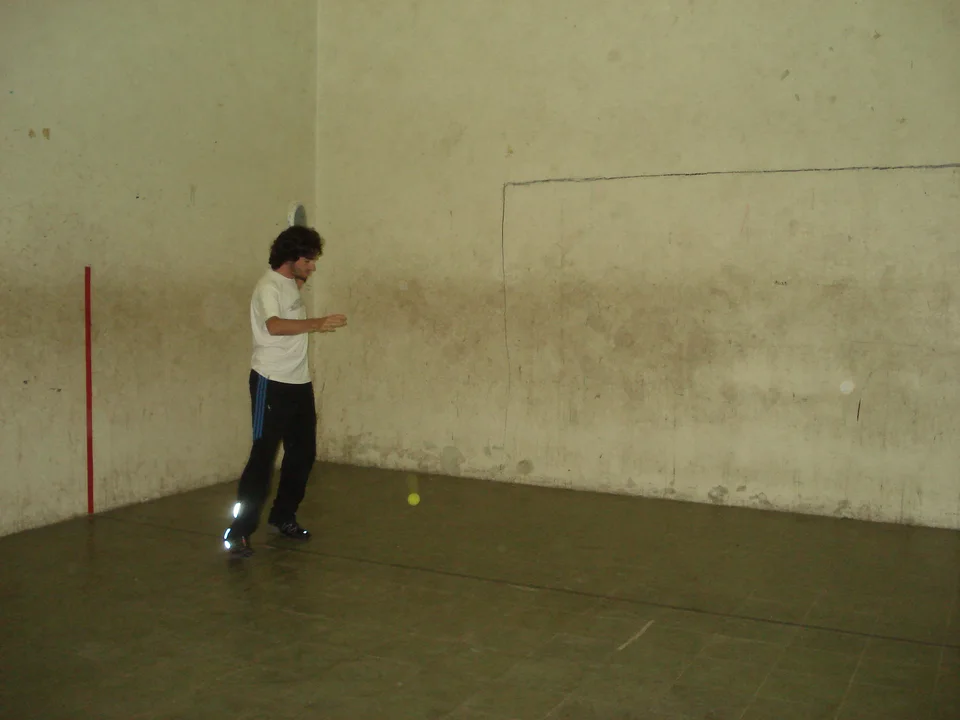 A padel player preparing a shot after a wall rebound